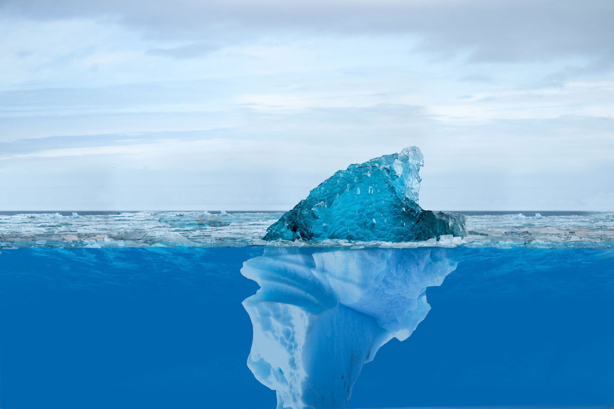 A photo of an iceberg where you can see above and below the water