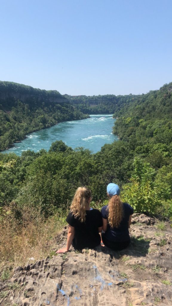 Two people looking out towards a river in the hills