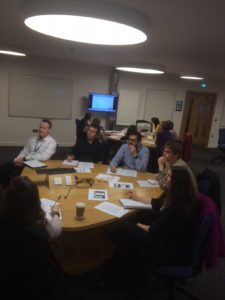 Session attendees seated round a table watching a usability testing video