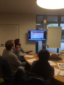 Session attendees seated round a table watching a usability testing video