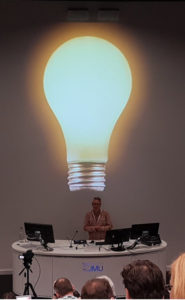 Neil Allison presenting a slide with a giant lightbulb on it