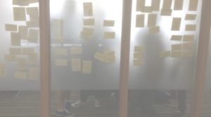 Post it notes and people seen through a glass wall