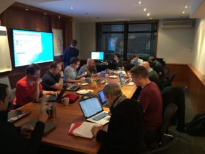 Room full of developers sat round a huge table all hard at work on laptops