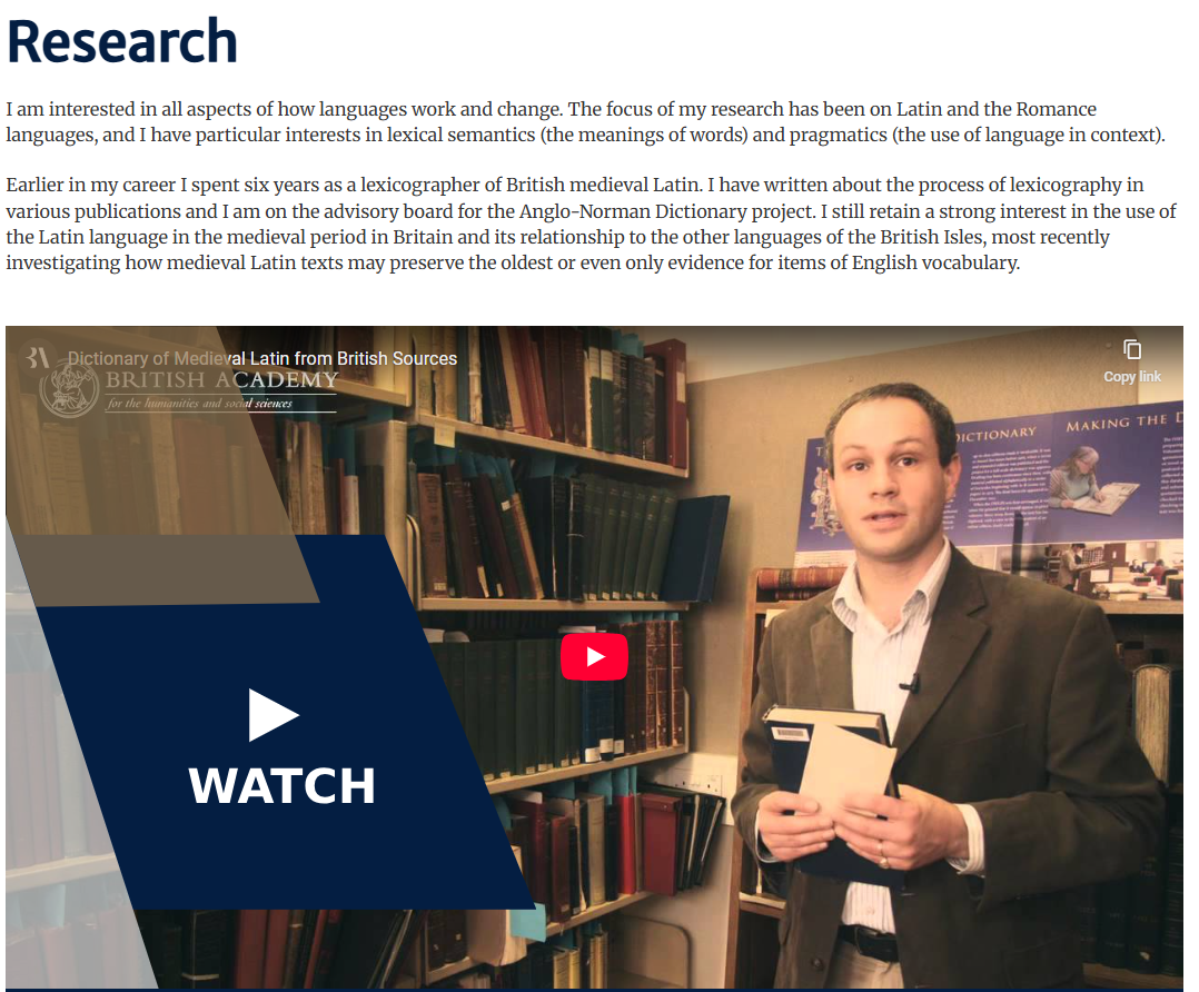 Research section of an academic from University of Oxford. It contains 2 paragraphs, with a video thumbnail displaying below. In the thumbnail, the academic is looking at the camera, holding a book.