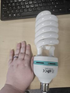 A large spiral lightbulb with a hand next to it