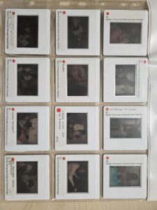 A clear binder page filled with photographic slides, the slides have white edges with a small window