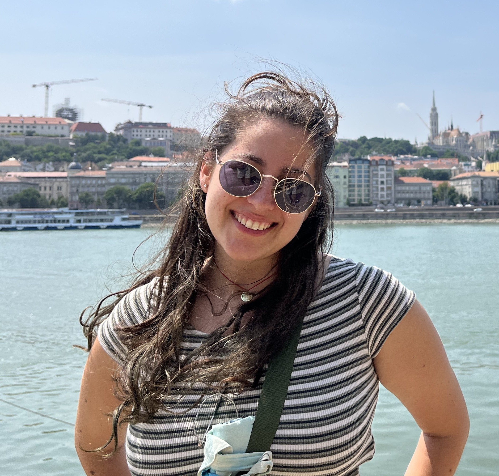 Photograph of Elisa stood in front of a river on a sunny day.