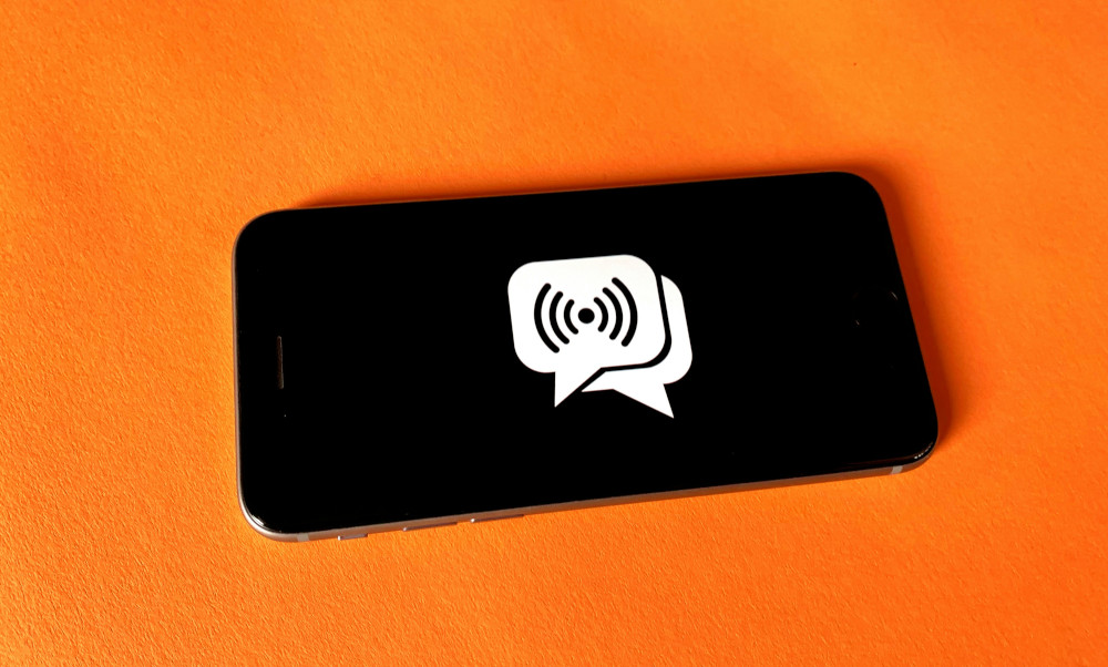 Mobile phone with chat emoji lying on orange square