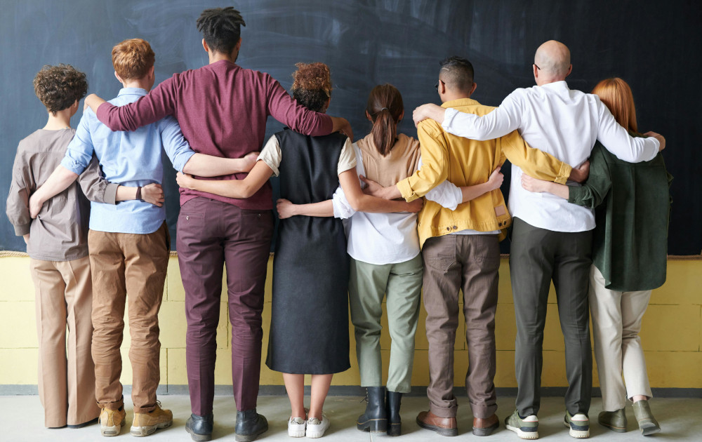 Student and staff linking arms facing blackboard