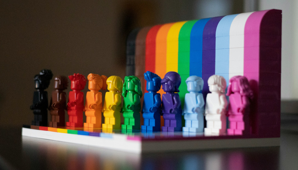 Photo of lego figures in rainbow colours standing on a rainbow platform.