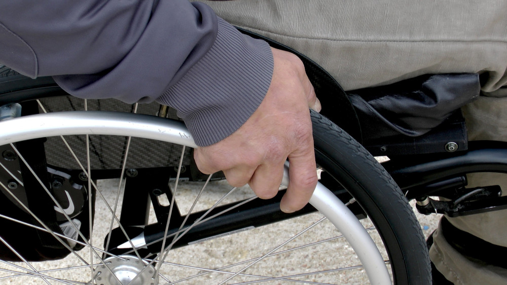 Photo of man in wheelchair zoomed in with his hand on wheel