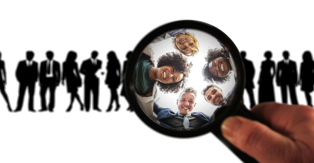 image of line of people silhouetted with magnifying glass bringing 5 people into focus
