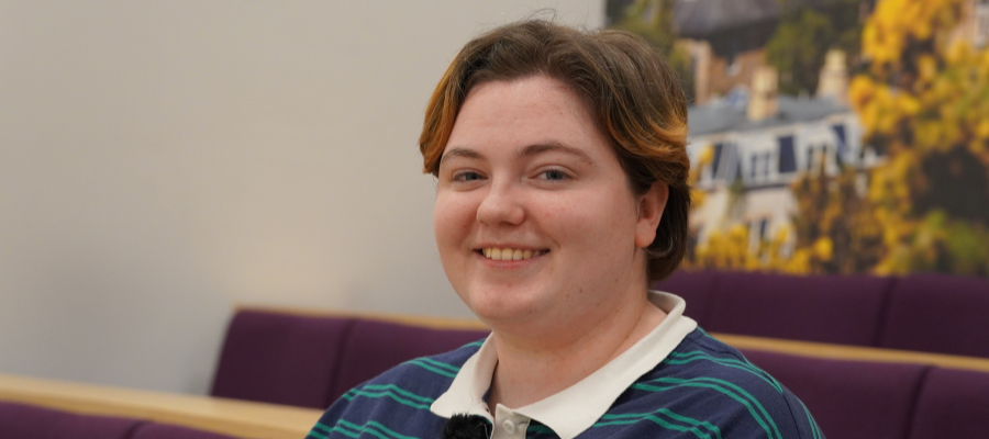 A close-up of Ailis smiling at the camera while sitting in a lecture theatre.