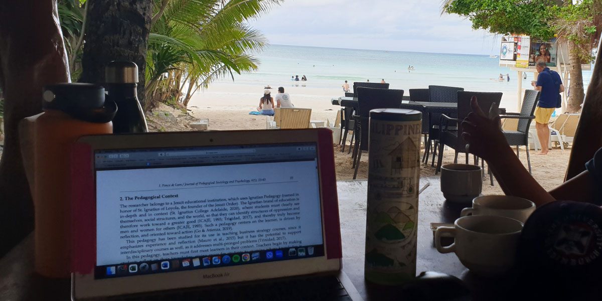 Laptop displaying study materials on table, with beach view.