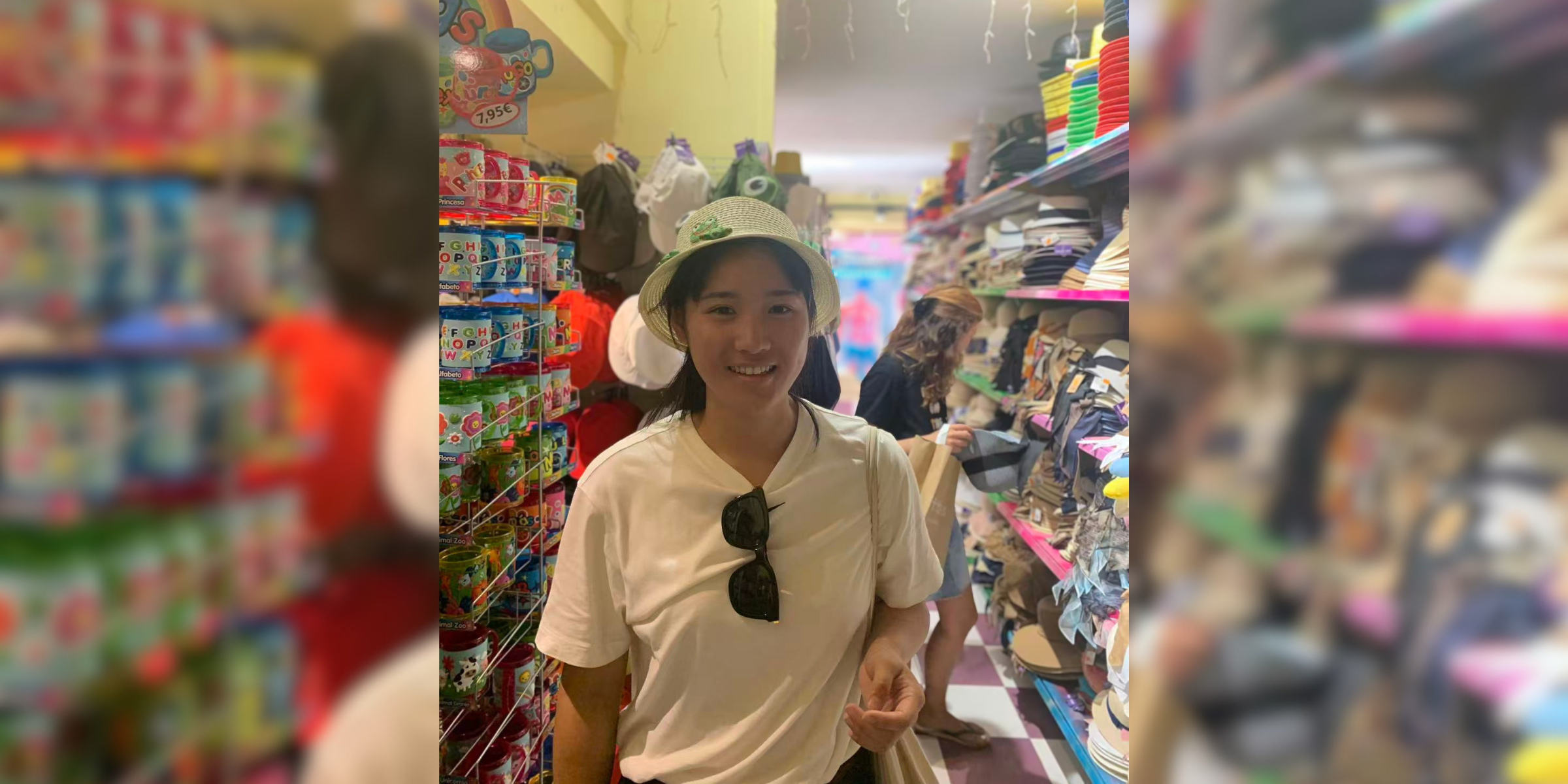 A person in a shop smiling for a photograph, while wearing a hat.